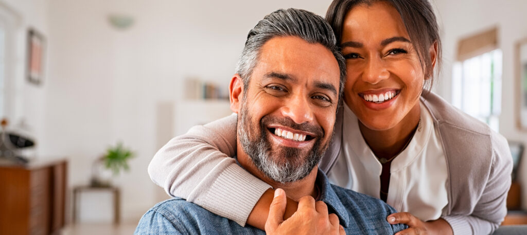 Un homme et une femme souriants avec la femme enlaçant l'homme, symbolisant la joie malgré les défis du sucre et du saccharose en dentisterie à la clinique Deslauriers Pissardo Jacques.