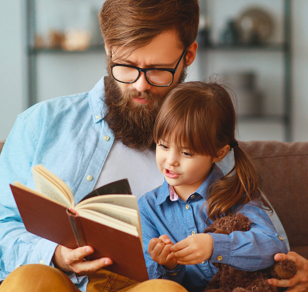 Petite fille et son papa regardant un livre pour se préparer avant la première visite chez le dentiste à la Clinique dentaire Deslauriers Pissardo Jacques.