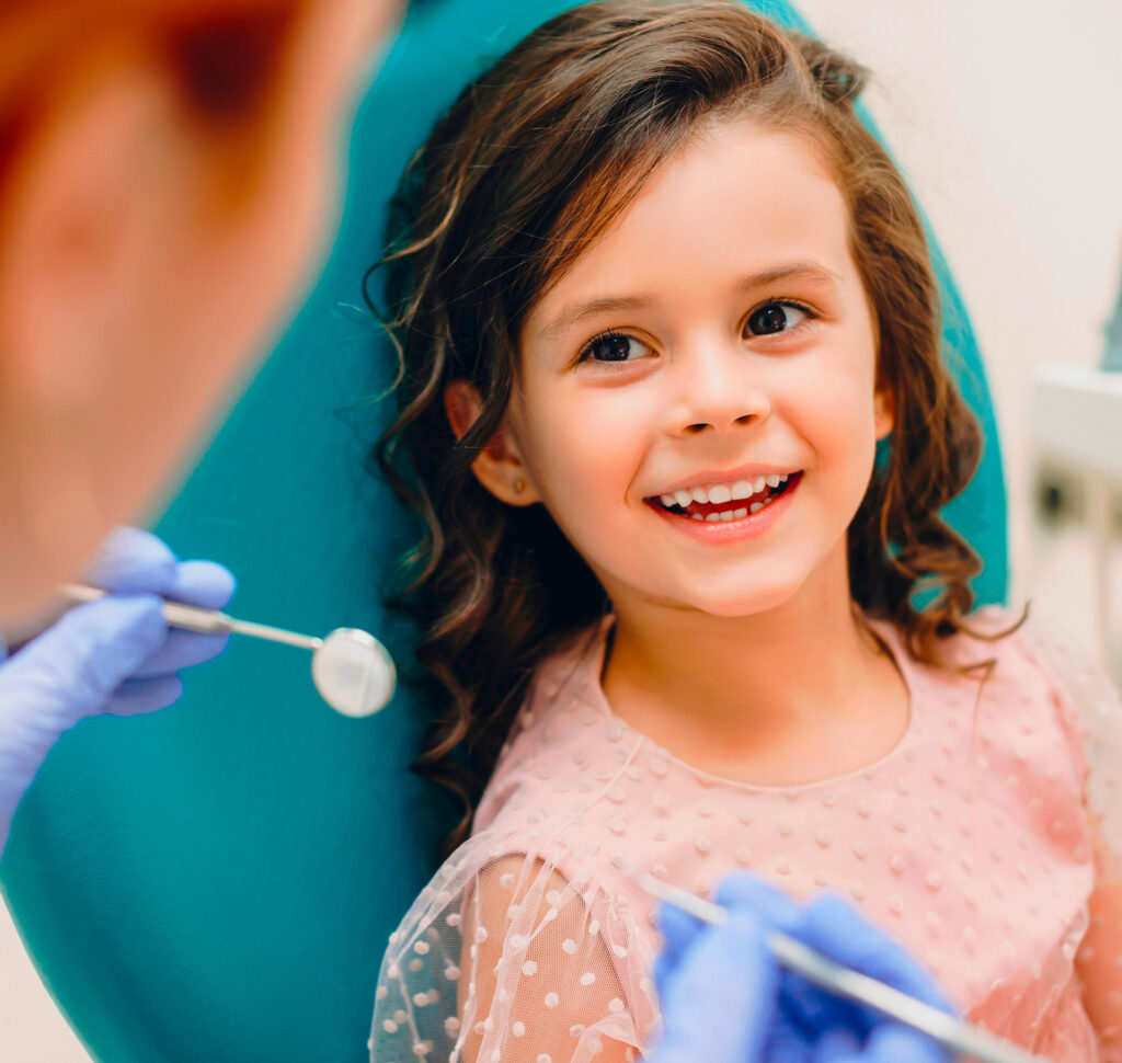 Une petite fille assise dans un fauteuil de dentiste lors de sa premiàre visite chez le dentiste à la Clinique dentaire Deslauriers.
